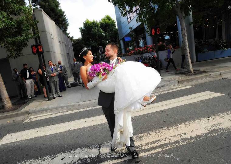 groom carrying bride while posing for photos on the streets of san francisco at event by bay area wedding planner